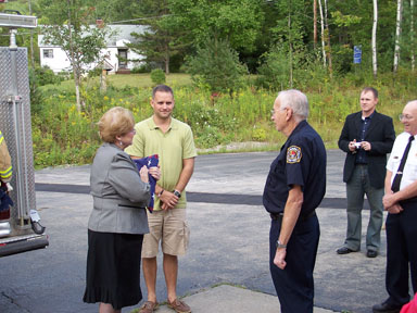 Mary and Sean Szymanski accept the flag from Duane Testut and Chief Roy Rizzo.