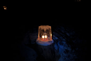 New lantern shining on a stump by the driveway.